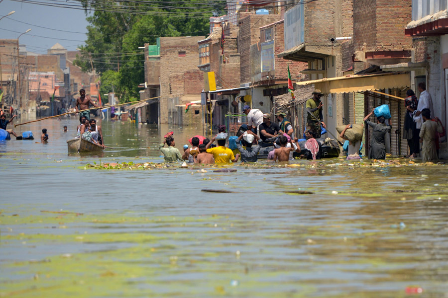洪水で一面が水に浸かった道路に集まる人々（シンド州ダードゥ地区ケアプール・ネイサン・シャー／パキスタン） Credit: DEC