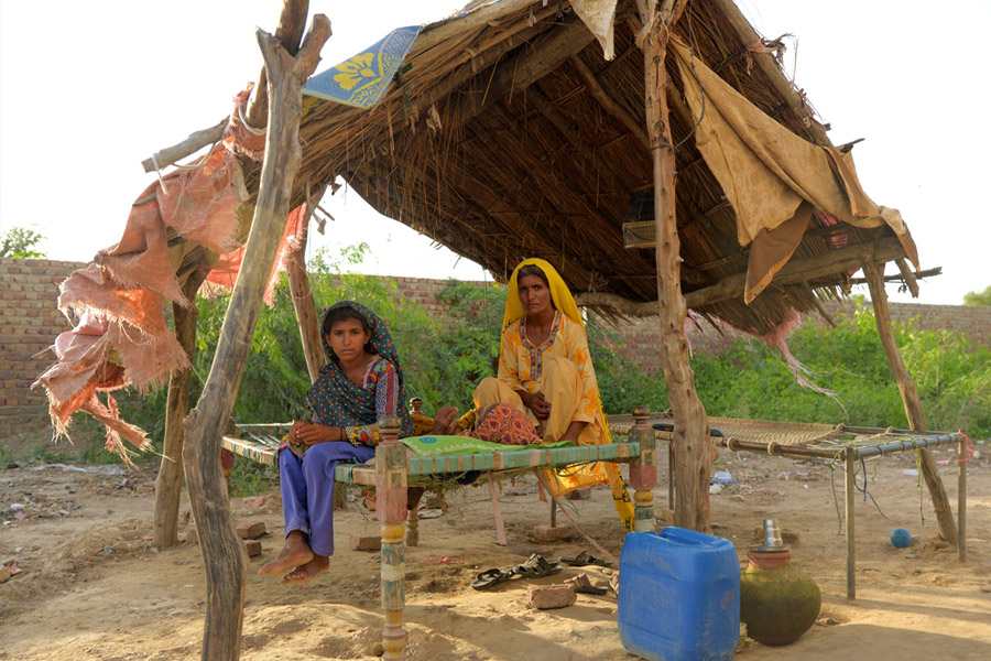 洪水で家を追われ、仮設住宅で娘と座るナスラ・ビビさん(36歳）（シンド州ジャムショロ地区／パキスタン）Credit: DEC