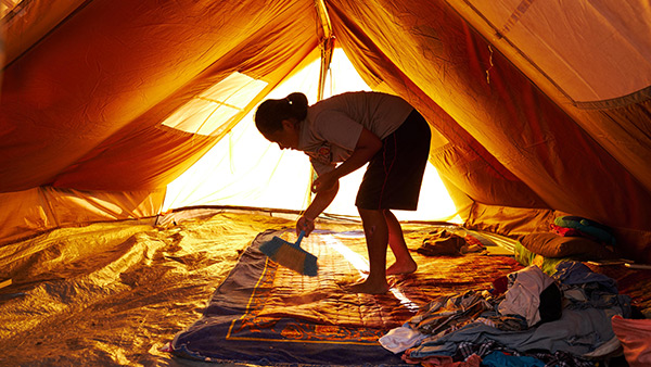 避難所の家族が眠るテントで砂埃等を掃除する女の子／10月7日／シギ県、インドネシア©Lewis Inman/Arete Stories/DEC