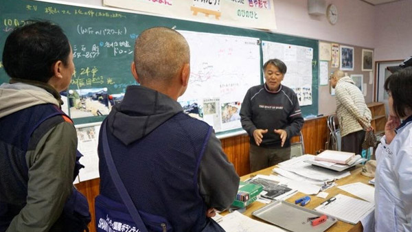 Staff from SVA, a JPF member NGO, listening about the extent of the damage from people at Saku Shiritsu Aonuma Elementary School which is serving as an evacuation center ©SVA