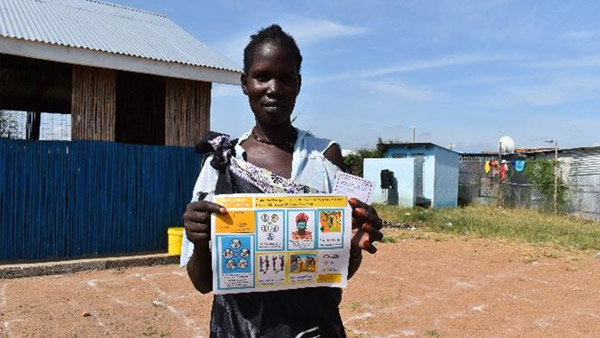 A beneficiary woman receiving the leaflet ©REALs