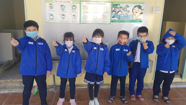 Children looking very happy; they’re wearing jackets with JPF and PLAN logos ©PLAN