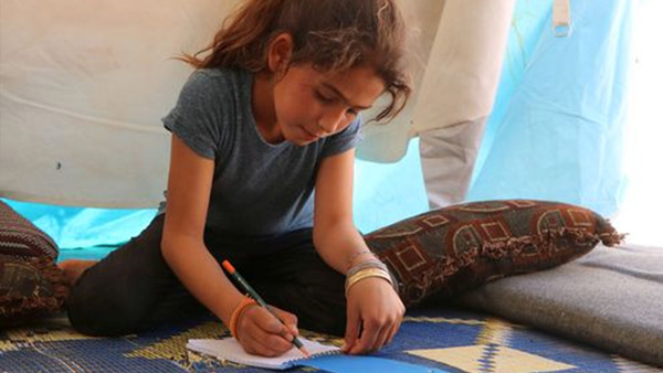 A Syrian child studies in her tent where she is taking shelter from the conflict ©WVJ